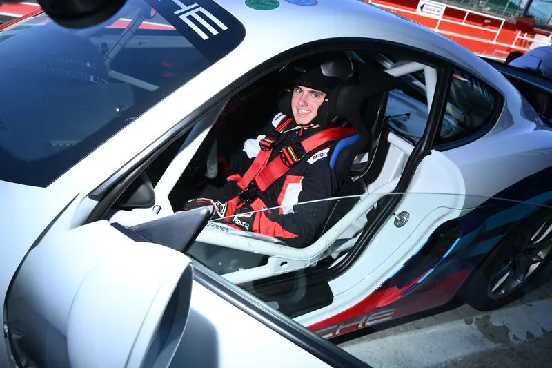 Pilota con casco nell'abitacolo della Porsche